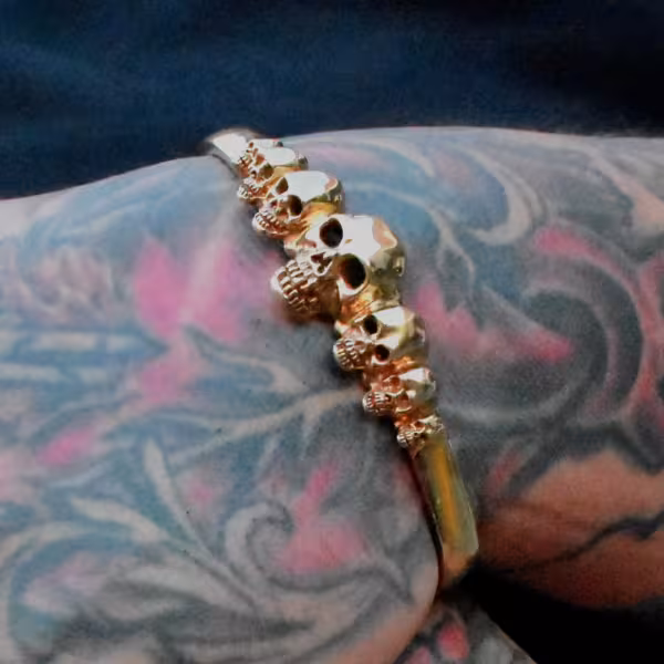 Bracelets, man's wrist with a gold seven Skull bracelet