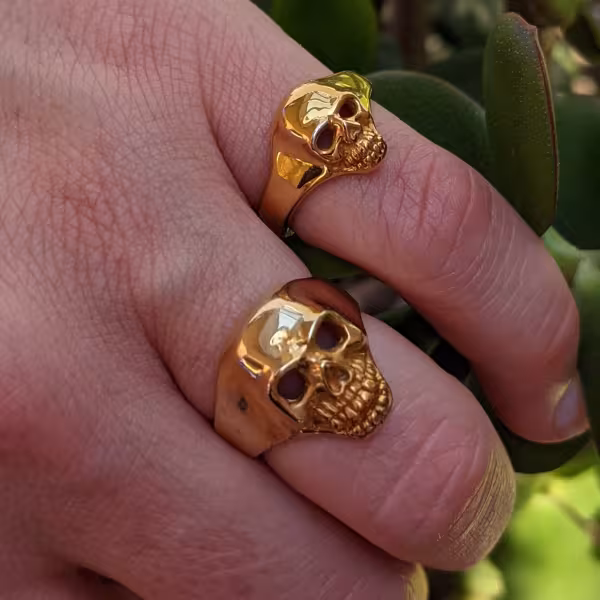 Skull rings in gold worn on a man's hand