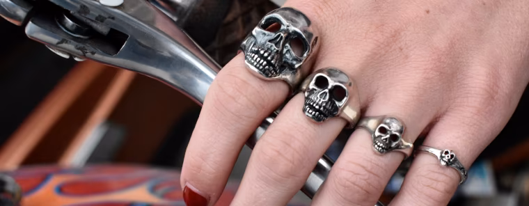 Skull rings, lady's hand with tiny, medium, large Skull rings over a Harley flame fuel tank